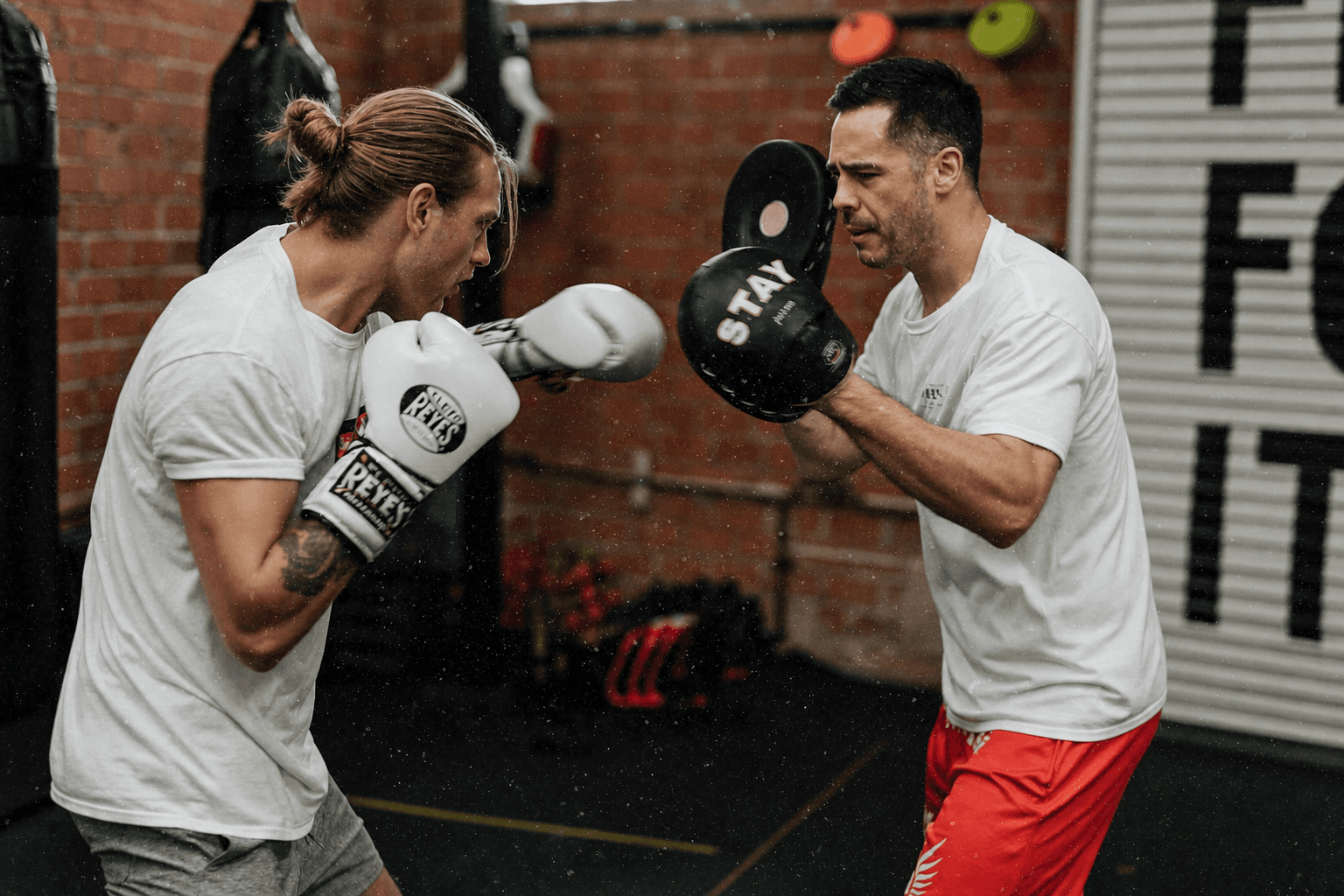 Boxer training combinations with a coach holding focus mitts